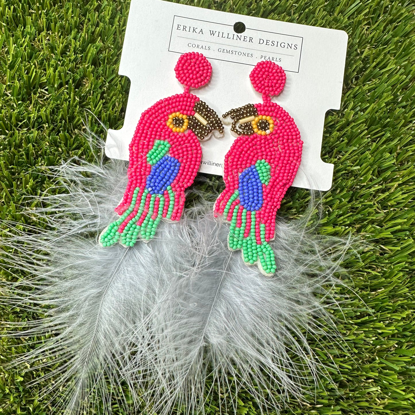 red parrot earrings with green and blue accents paired with white feather ending