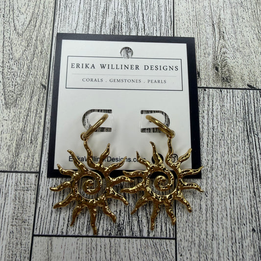 Gold sun-shaped earrings on a branded card with 'Erika Willliner Designs' on a wooden surface.