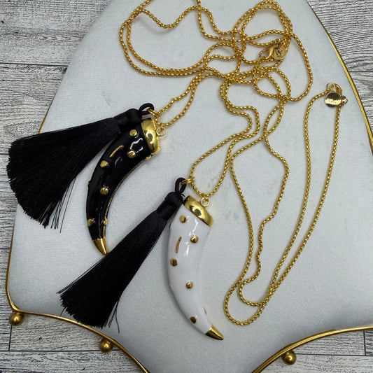 Necklace with black tassels and gold accents on a white plate