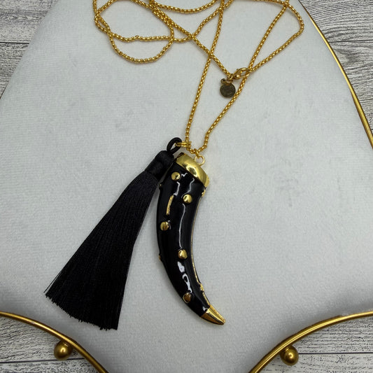 Black tassel pendant with gold accents on a gold chain against a white background