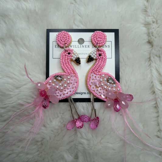 Pink beaded earrings on a branded card against a white fur background
