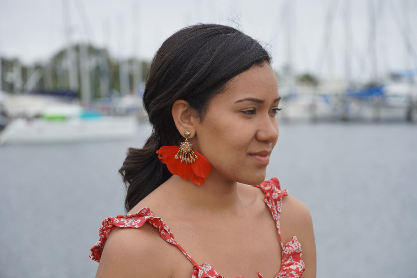model wearing red feather earrings