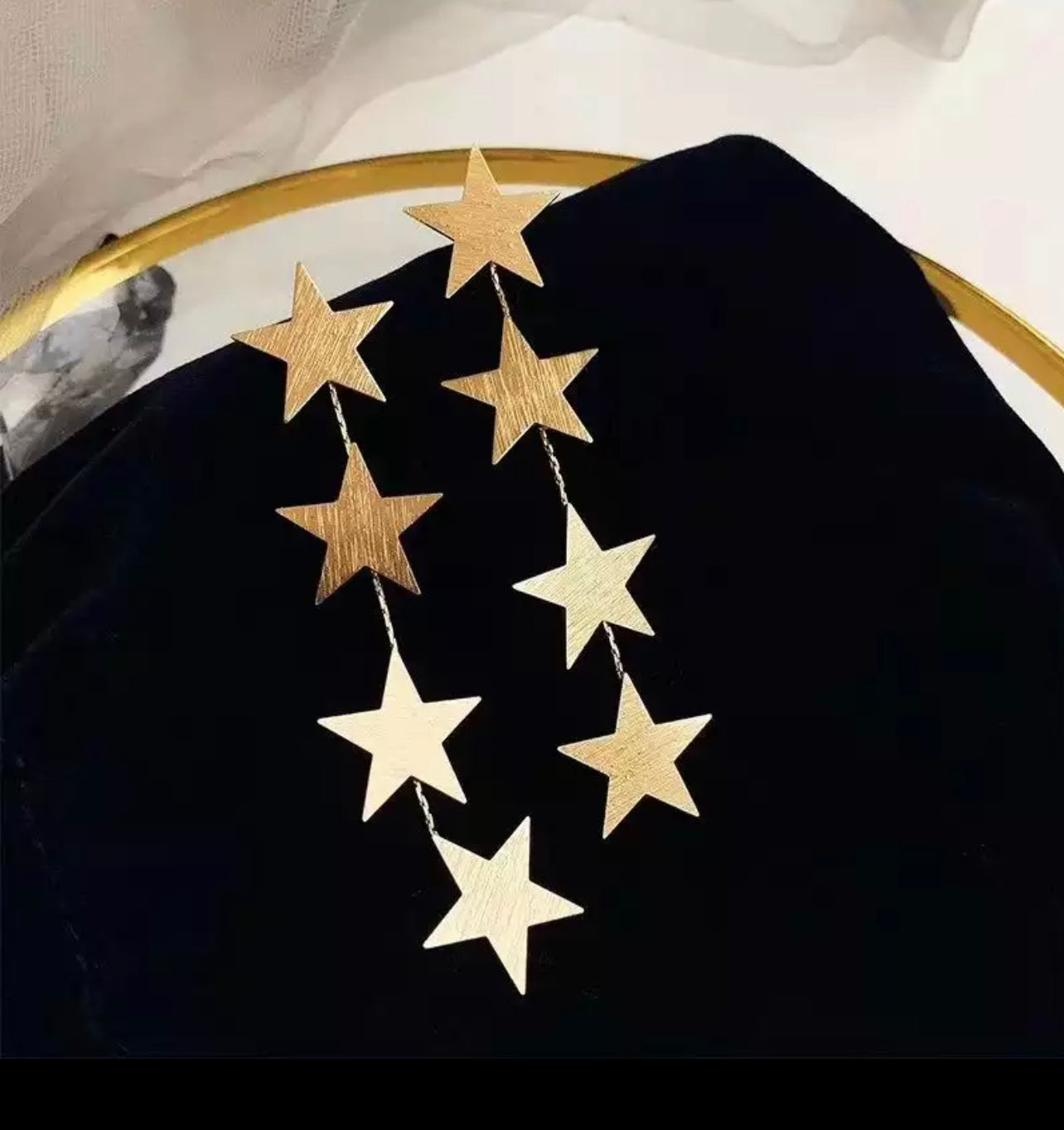 star dangle earrings laying on black velvet backdrop