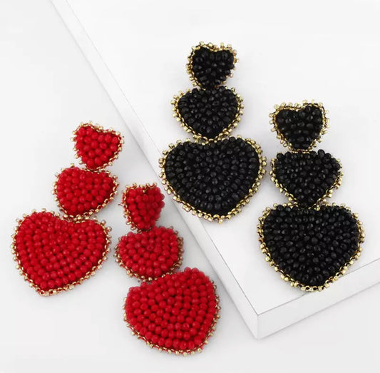 black and red tri heart earrings on white background