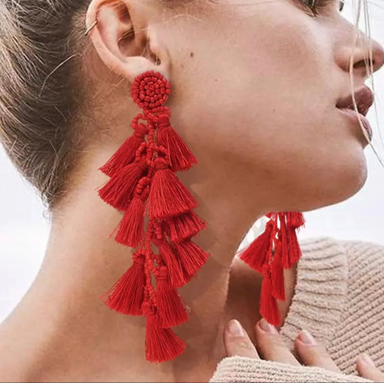 side view of female wearing red tassel earrings